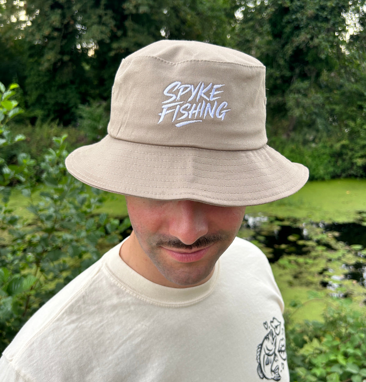 Bob de pêche beige Spyke Fishing porté par un homme
